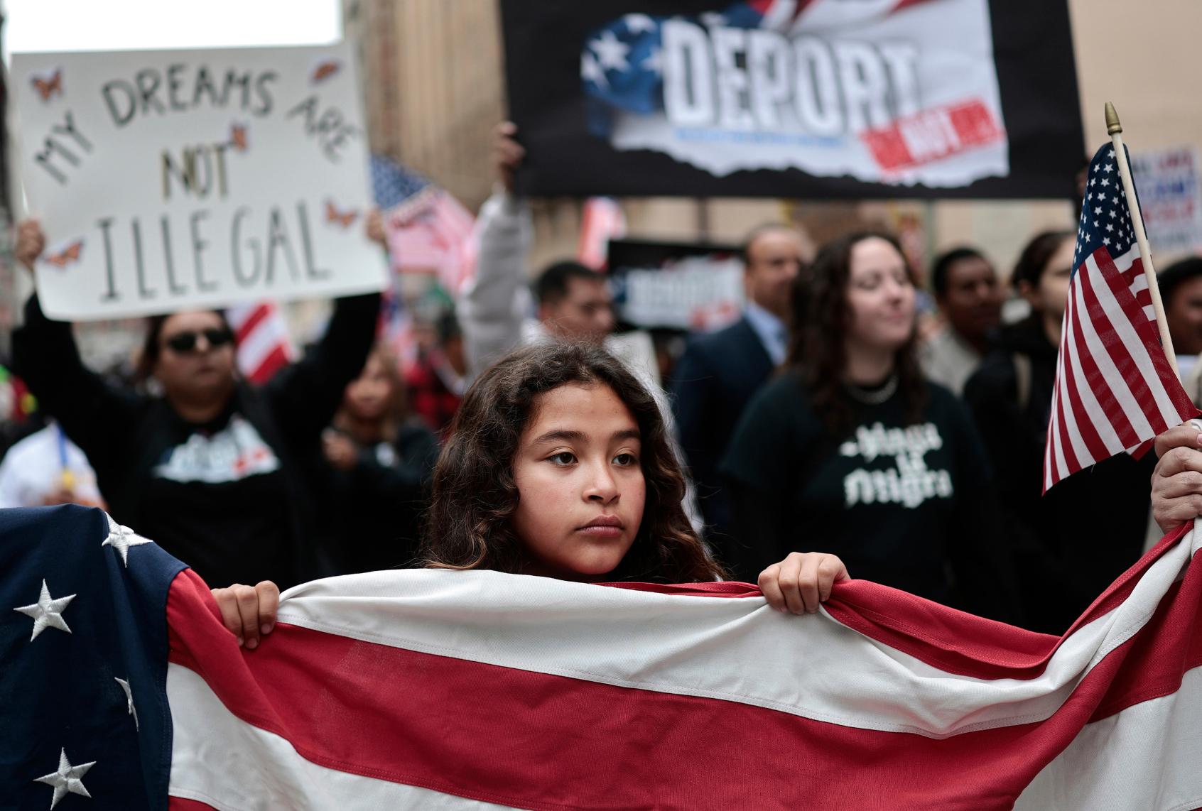 A demonstrator helps carry an American flag as immigrants rights supporters march downtown during a 'March for Dignity' on March 01, 2025 in Los Angeles, California. (Mario Tama/Getty Images)